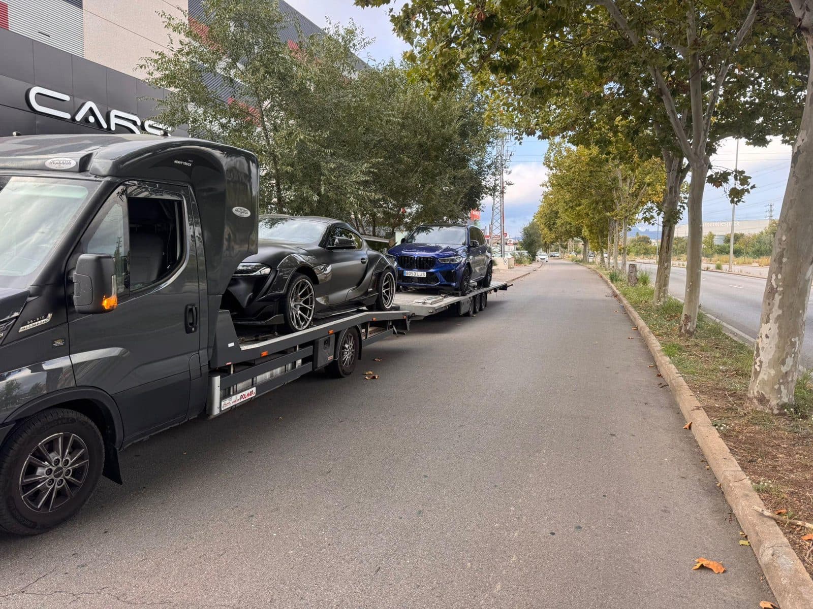 Laweta z dwoma samochodami sportowymi na ulicy w Hiszpanii